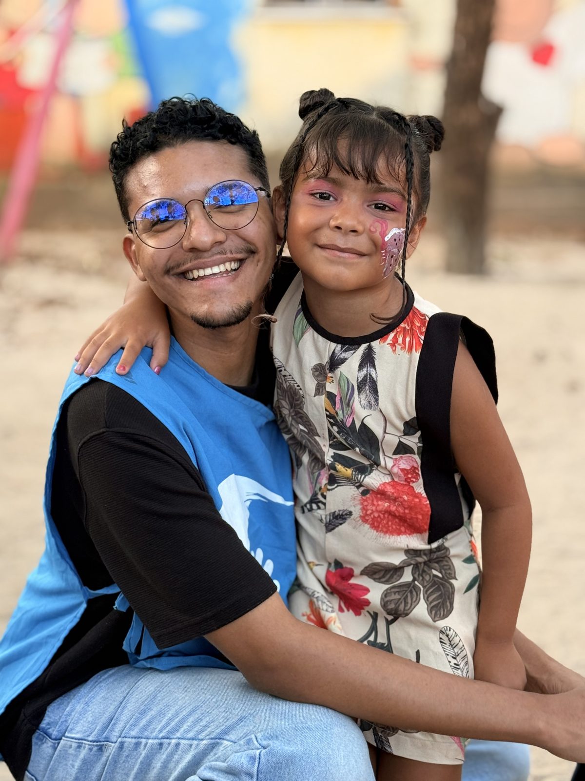 Voluntário abraçando uma criança, ambos sorrindo.